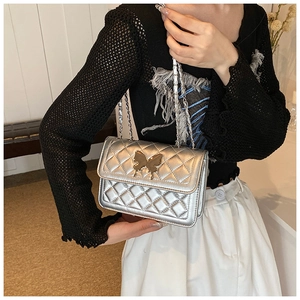Détail du sac matelassé argenté avec fermoir papillon doré et bandoulière chaîne