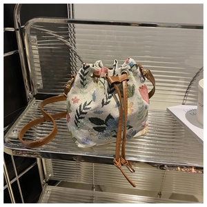 Detail of floral tapestry bucket bag with brown leather drawstring and golden hardware