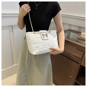 Macro shot of white quilted tote bag featuring a silver bow metal buckle and gold chain strap