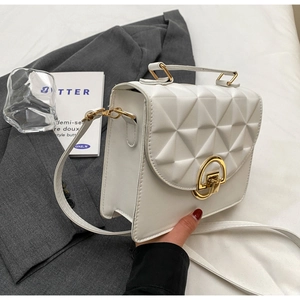 Detailed view of white textured leather crossbody bag with elegant gold hardware
