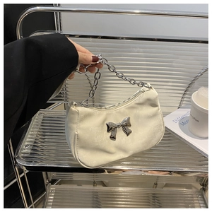 Detail of cream shoulder bag with large silver bow buckle and chunky chain handle