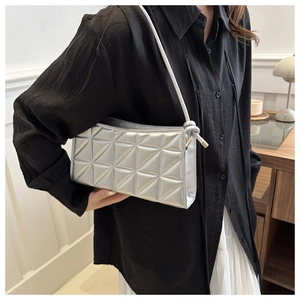 Detail of silver geometric quilted shoulder bag with knotted strap and metallic texture
