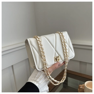 Detail of white quilted crossbody bag featuring gold chain strap and metal twist lock