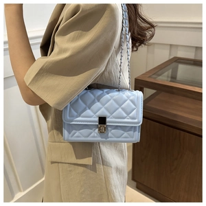 Détail d'un sac bandoulière matelassé bleu clair avec chaîne et fermoir pivotant