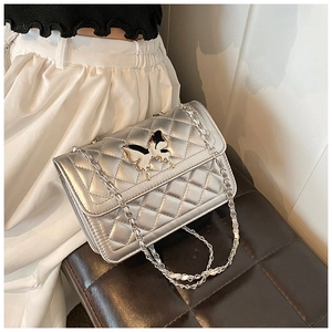 Détail du sac bandoulière argenté avec fermoir papillon et bandoulière chaîne