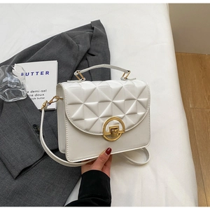 Close-up of white quilted crossbody bag with golden rotary lock and chain detail