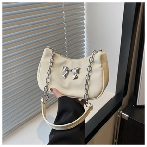 Detail of hobo bag with silver metallic bow and chain strap on fabric material