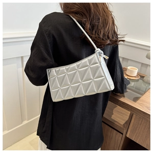 Close-up of a silver quilted handbag with geometric triangle stitching and metallic finish