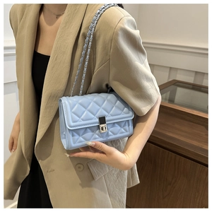 Close-up of light blue quilted crossbody bag with classic chain strap on a model