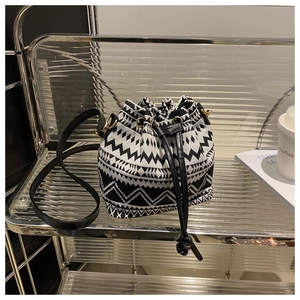 Close-up of geometric ethnic canvas bucket bag with drawstring and gold-tone hardware