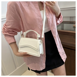 Detail of white PU leather crossbody bag with knot handle worn with pink shirt