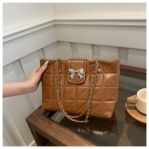 Detailed shot of brown quilted tote bag with silver bow accent and gold chain strap