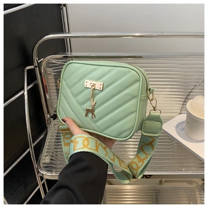 Detail of light green square crossbody bag with V-quilted texture and gold deer charm