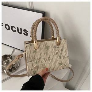 Detail of hand-woven beige bag with floral embroidery and adjustable leather strap