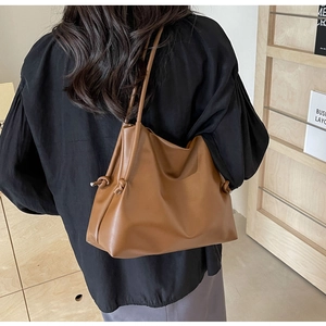 Dettaglio della borsa tote color caramello con coulisse laterale e texture liscia