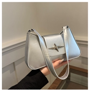 Detail of silver metallic underarm bag featuring a star-shaped buckle and Y2K aesthetic
