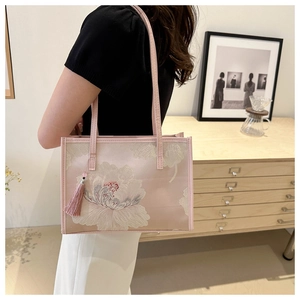 Détail de la broderie florale blanche et du gland rose sur un sac cabas chinois