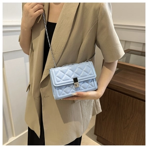 Detail of light blue quilted crossbody bag with silver chain strap and metal lock