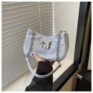 Detail of light blue satin underarm bag with silver bow accent and chunky metal chain