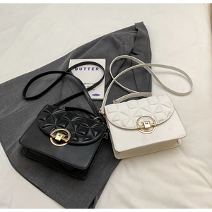 Flat lay of black and white cross-body bags with 3D diamond texture and gold buckles