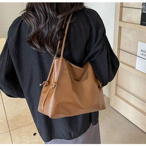 Detail of a brown leather shoulder bag with drawstring knot and fine grainy texture