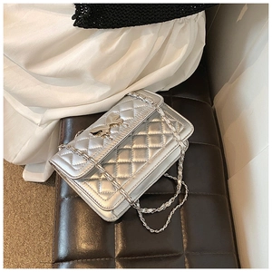 Détail du sac bandoulière argenté matelassé avec fermoir nœud et bandoulière chaîne