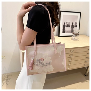 Close-up of pink tote bag with white floral embroidery and silk tassel detail