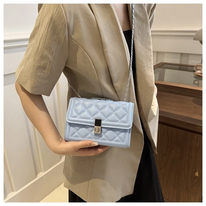 Detail of light blue quilted crossbody bag with metal clasp and elegant chain strap