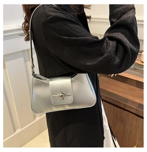 Detail of silver metallic underarm bag featuring a star-shaped buckle and fine stitching