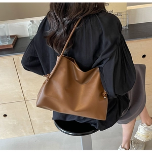 Dettaglio della borsa tote in pelle marrone vintage con nodo e tracolla sottile