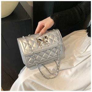 Détail du sac bandoulière argenté matelassé avec fermoir papillon et bandoulière chaîne