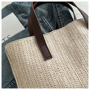 Detail of herringbone weave texture and dark brown leather handles on woven tote bag