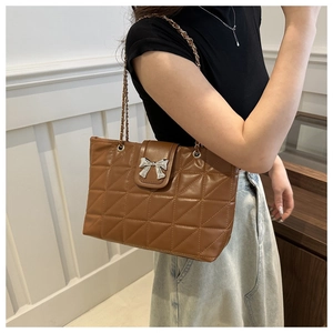 Detail of caramel brown quilted tote bag with silver bow clasp and chain strap