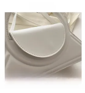 Dettaglio ravvicinato di una borsa in pelle bianca con design triangolare unico e cuciture