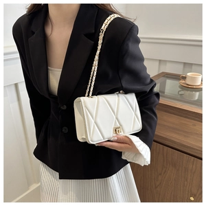 Detail of white quilted crossbody bag with gold chain strap and square turn-lock closure