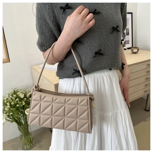 Close-up of geometric quilted beige shoulder bag with gold hardware and fine stitching