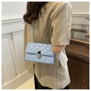 Détail du sac matelassé bleu clair avec bandoulière chaîne sur un blazer beige
