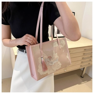 Détail du sac cabas rose avec broderie florale élégante et pendentif à pompon chic