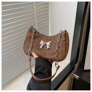 Detail of a brown suede hobo bag featuring a silver bow buckle and chain shoulder strap