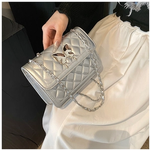 Détail du sac bandoulière matelassé argenté avec fermoir papillon et bandoulière chaîne