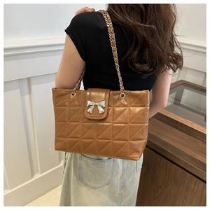 Detail of soft quilted brown tote bag featuring silver bow buckle and metal chain strap