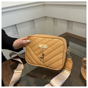 Close-up of khaki crossbody bag featuring V-quilted stitching and golden deer pendant