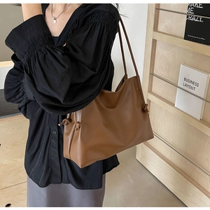 Detail of a brown leather shoulder bag featuring a unique side knot and soft texture