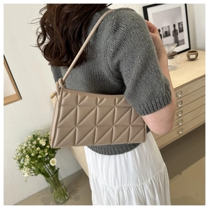 Detail of beige geometric quilted shoulder bag with triangular embossed leather texture