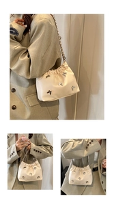 Details der beigen Plissee-Beuteltasche mit silbernen Metallschleifen und Kette