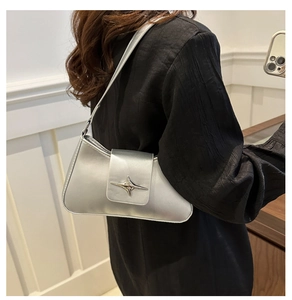 Detail of silver metallic baguette bag with a stylish star-shaped buckle on a black shirt