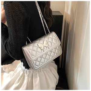 Détail du sac à bandoulière matelassé argenté avec fermoir papillon et chaîne