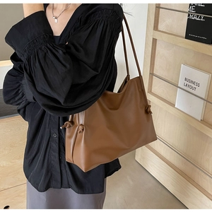 Minimalist caramel brown leather tote bag with side knot detail shown on a model