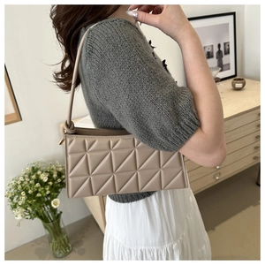 Detail of khaki quilted baguette bag with unique knotted shoulder strap on model