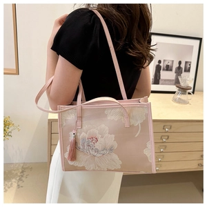 Détail du sac cabas rose brodé de motifs floraux avec accessoire de gland en soie